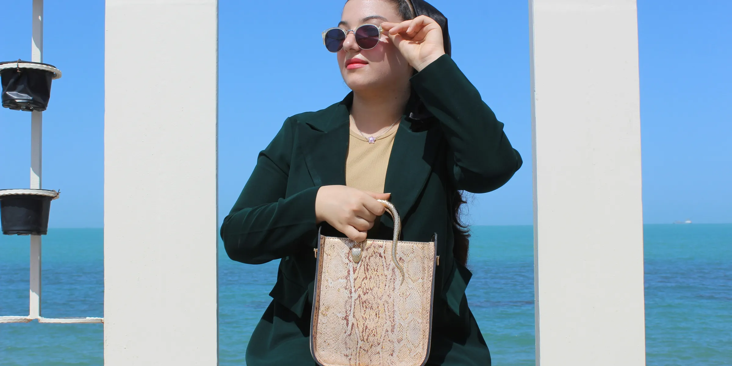 Woman in sunglasses holds a patterned tote bag.