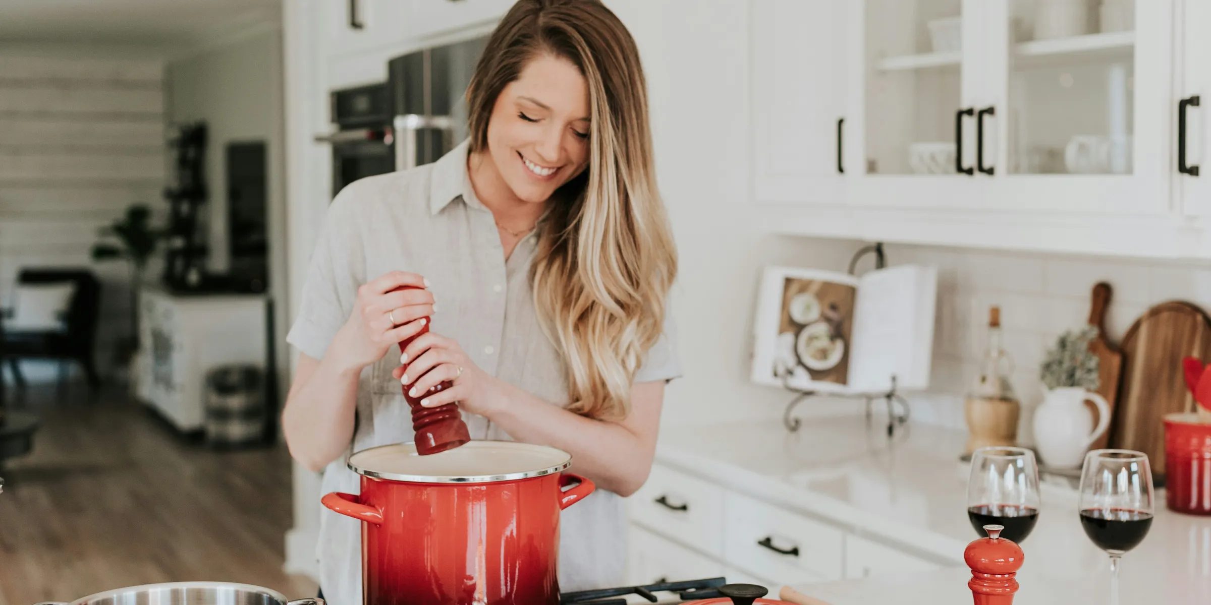 smiling woman standing and putting pepper on stock pot