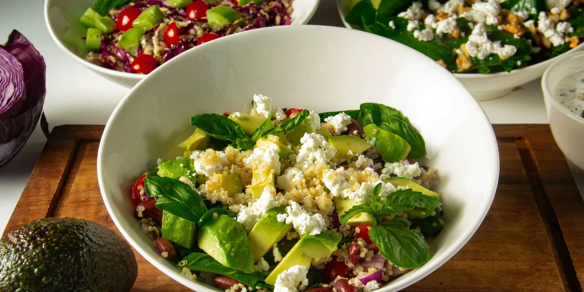 three bowls of salad on a cutting board