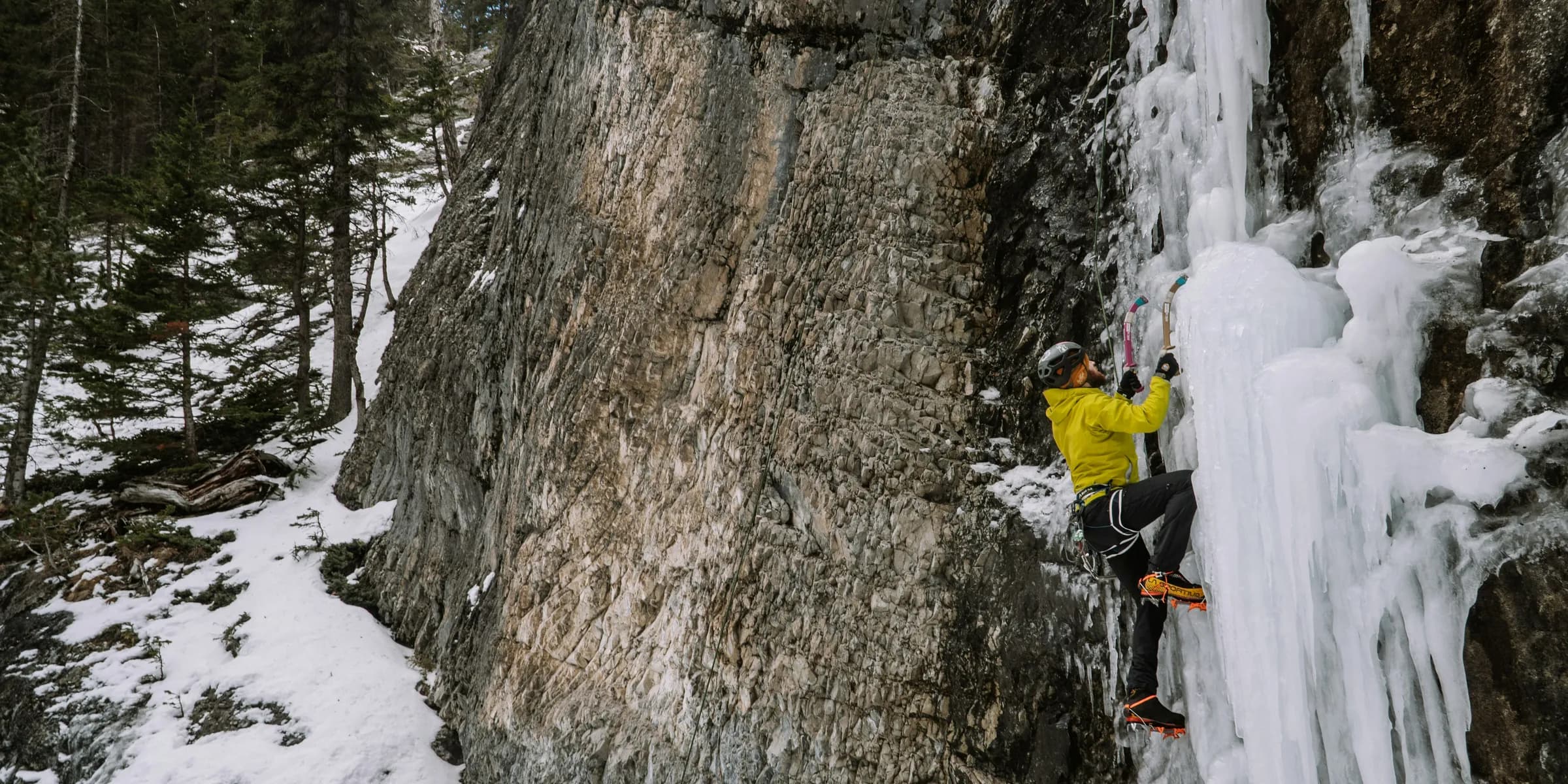 a man climbing up the side of a snow covered mountain