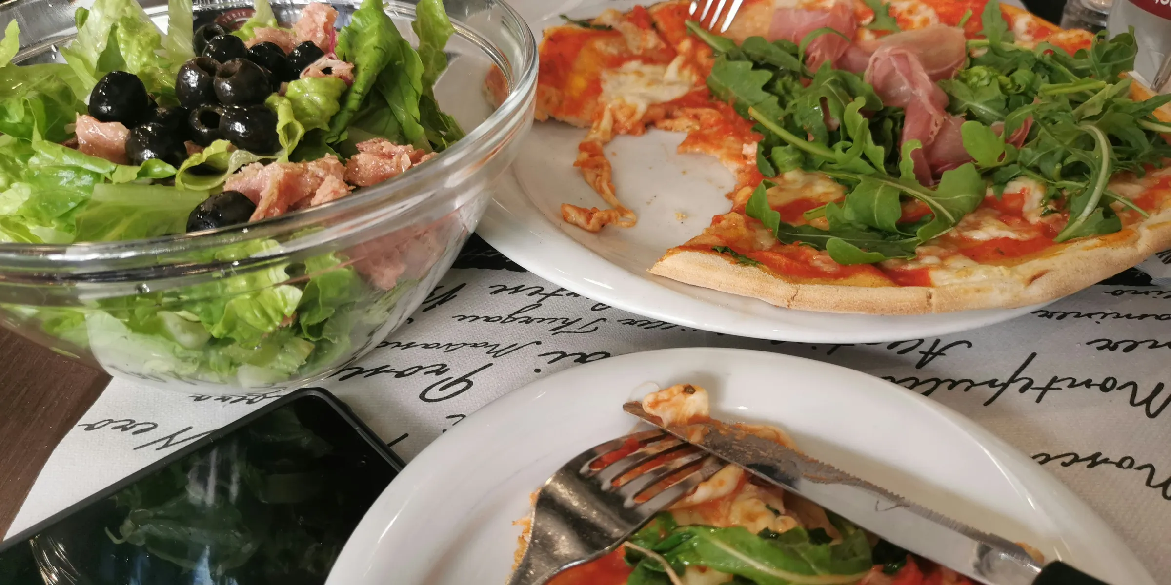 a table topped with plates of pizza and salad