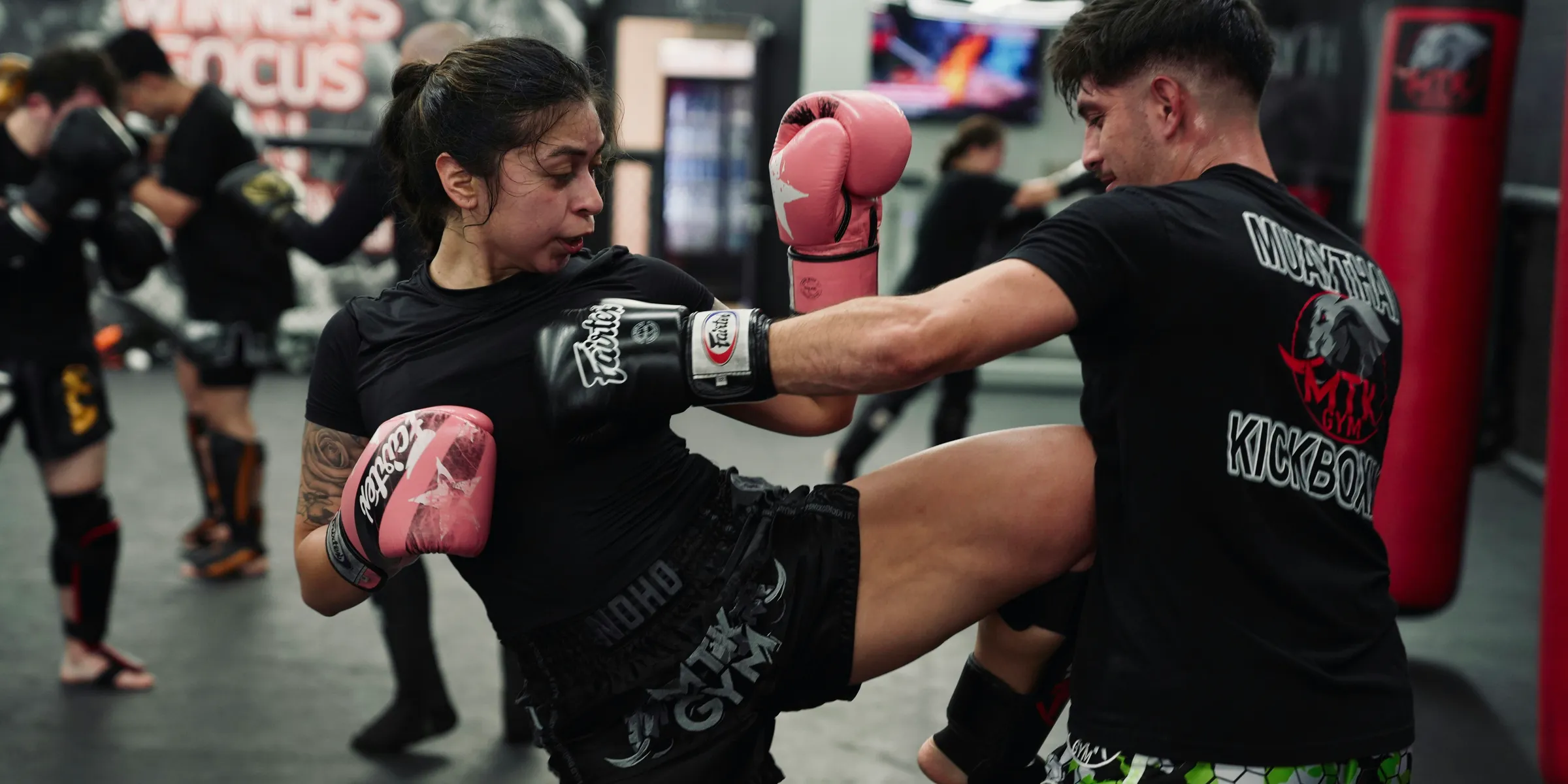 Woman kicks man during muay thai training session