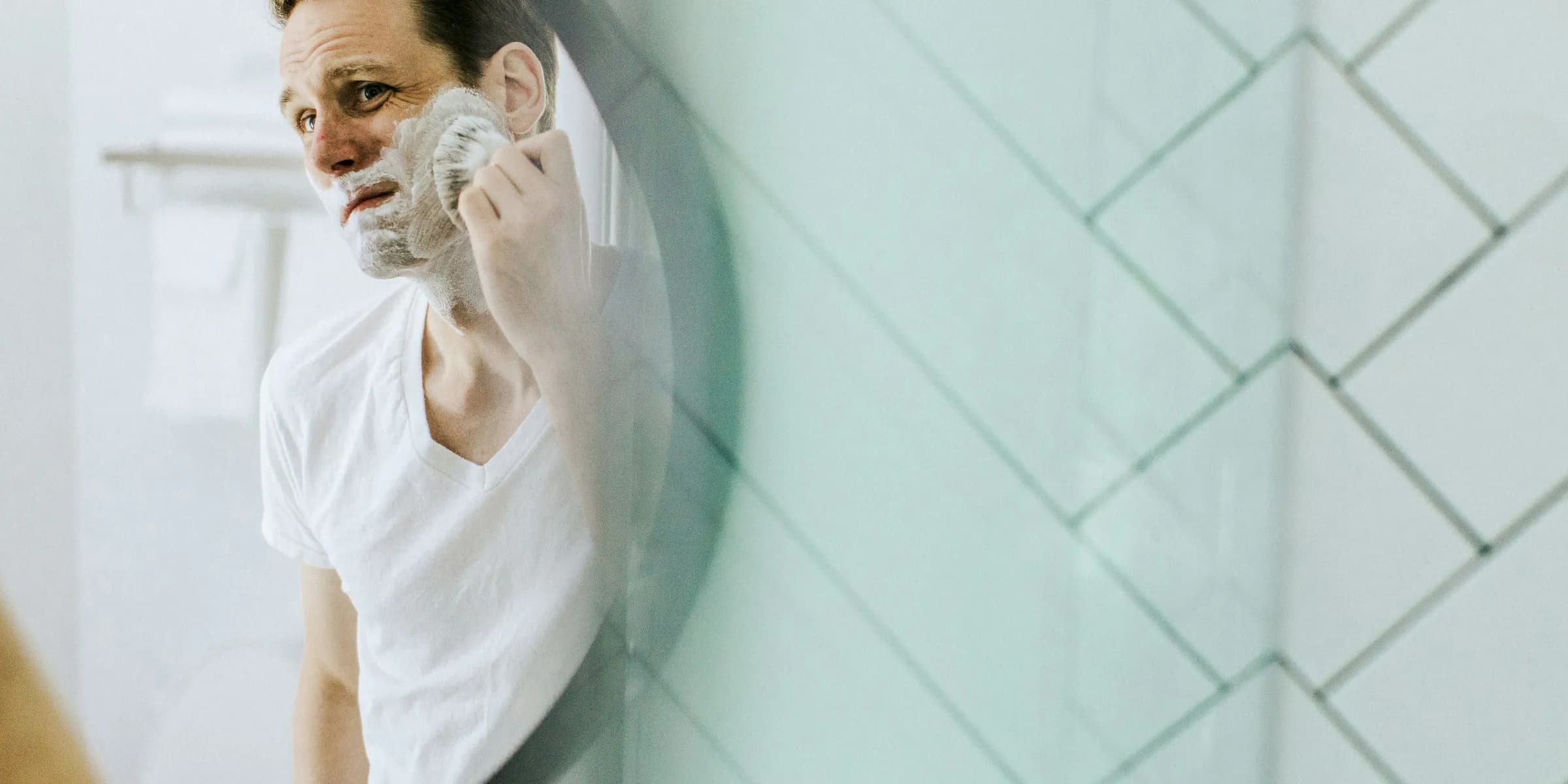 man shaving in front of mirror