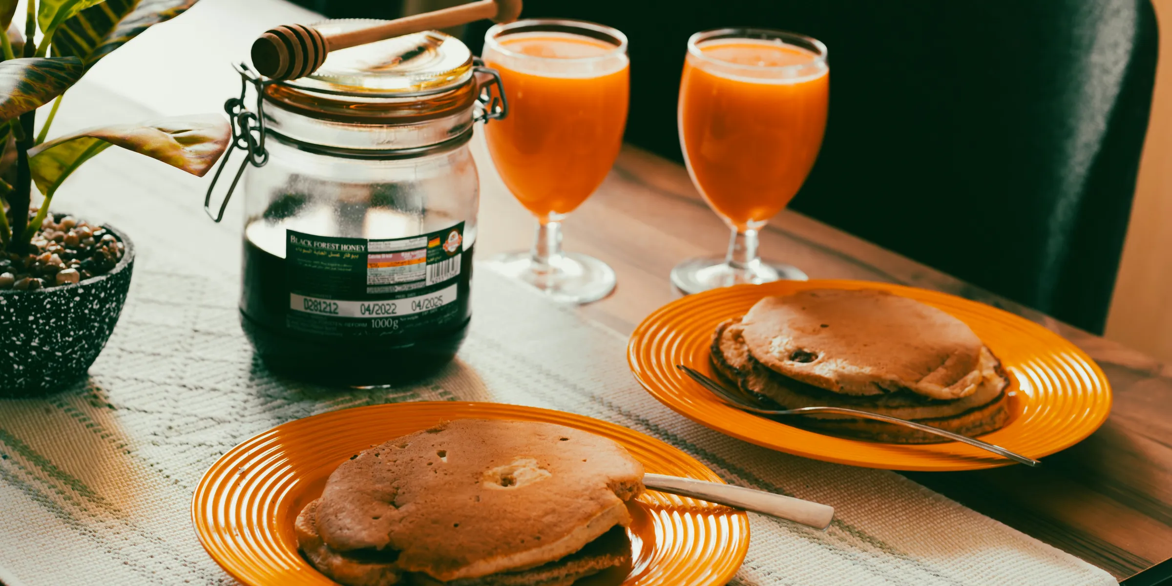 a table with two plates of pancakes and two glasses of orange juice