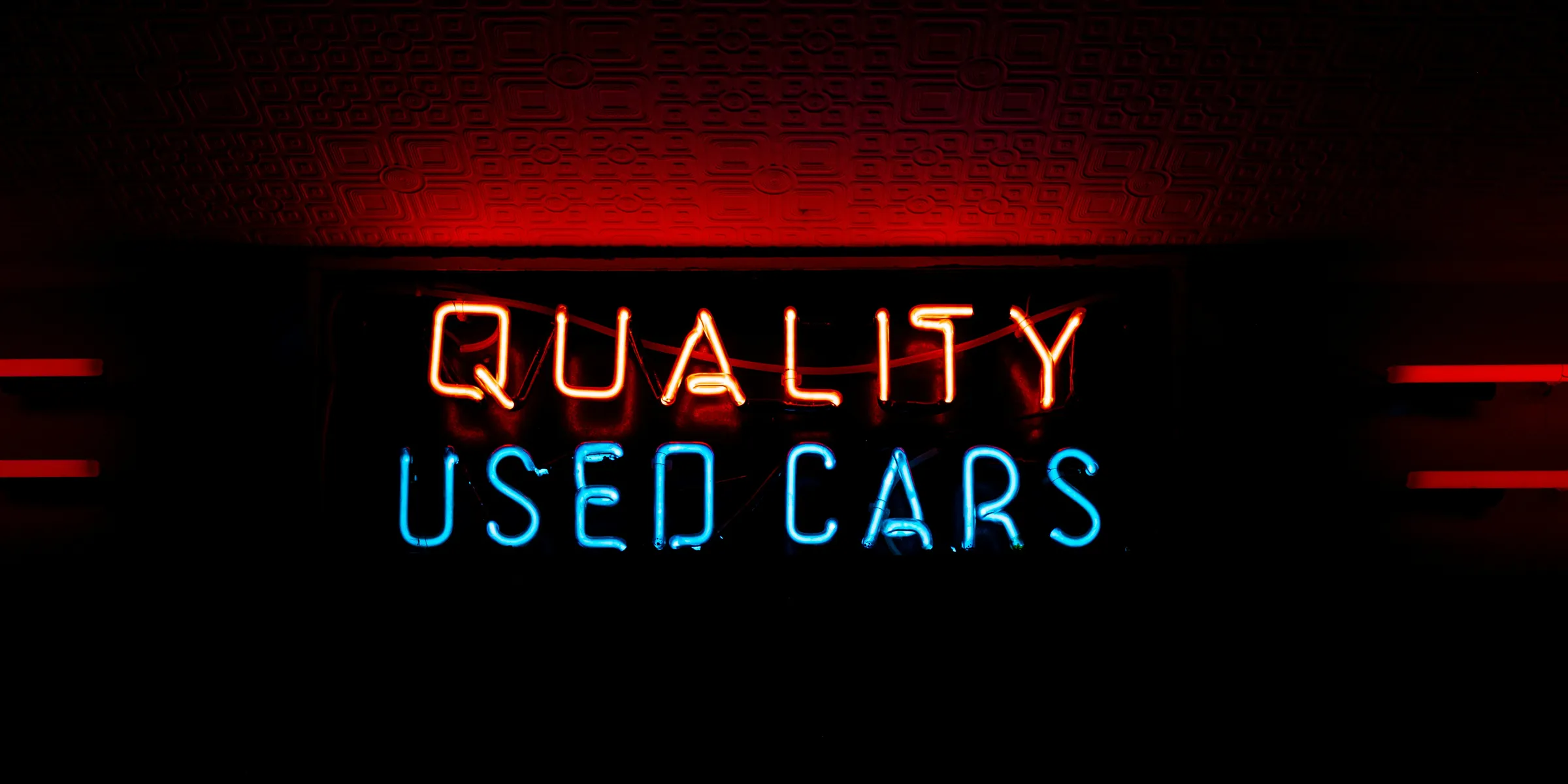 a neon sign that reads quality used cars