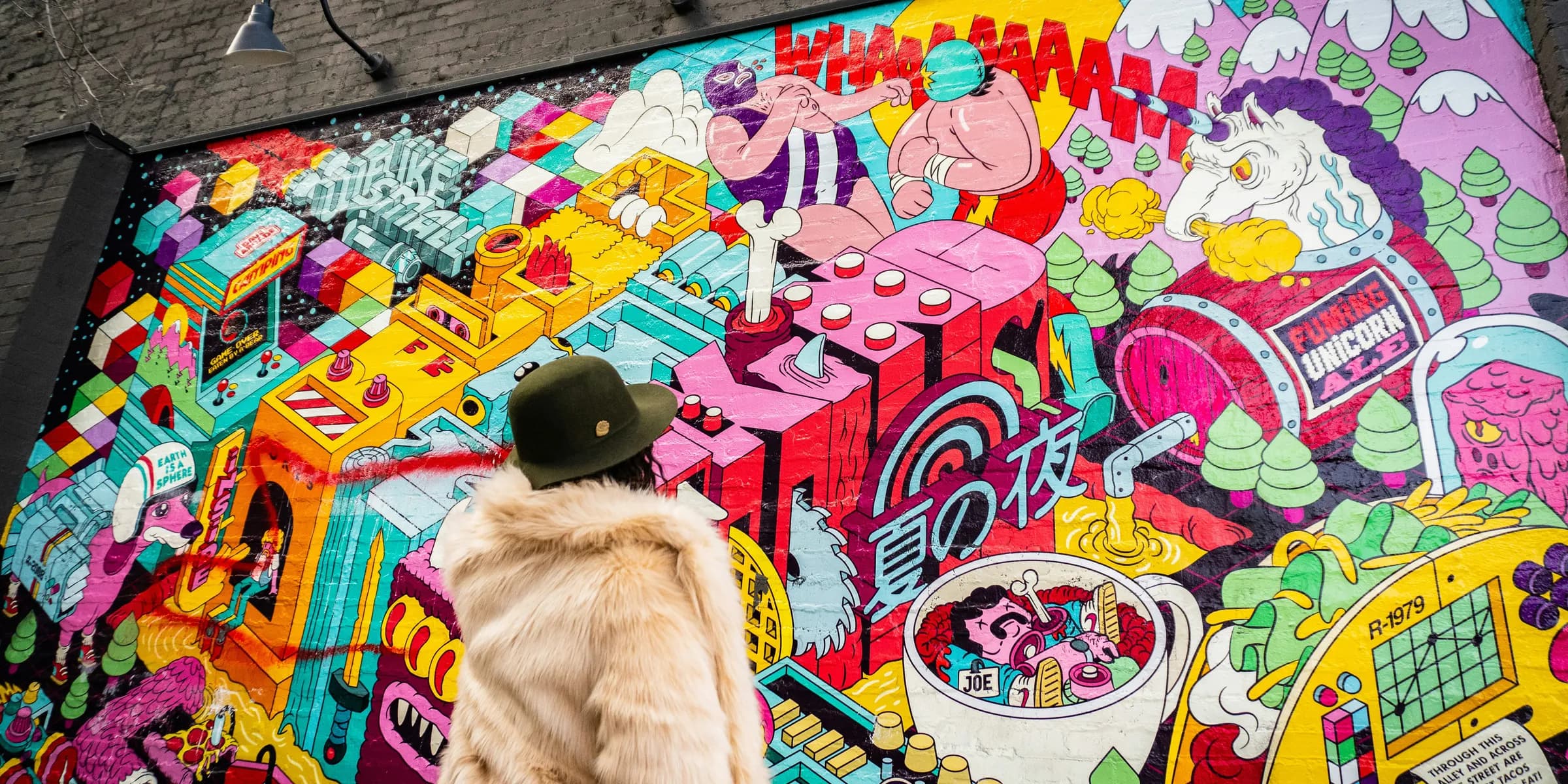 person wearing gray fur coat looking at graffiti during daytime