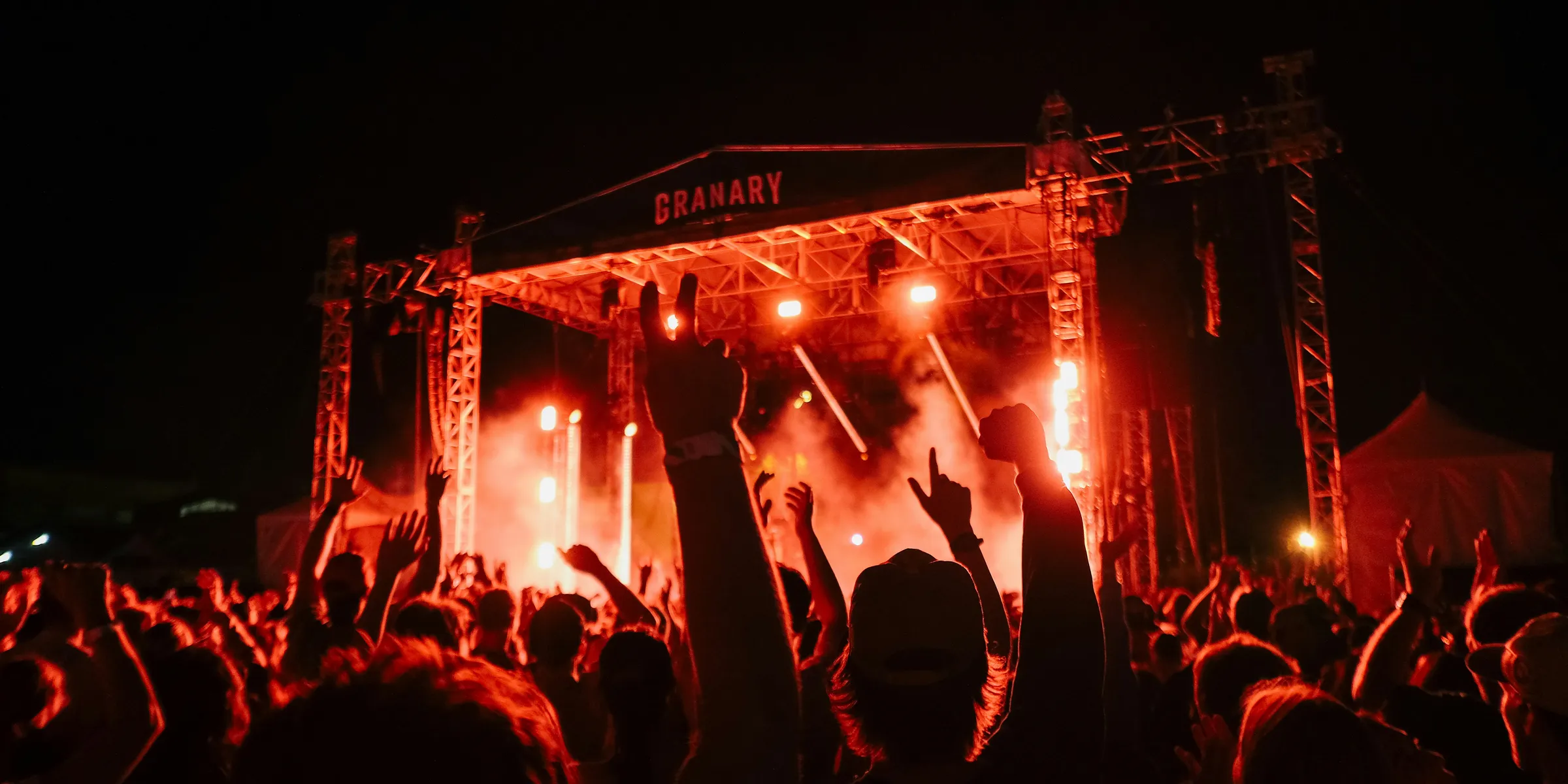 A crowd of people at a concert with their hands in the air