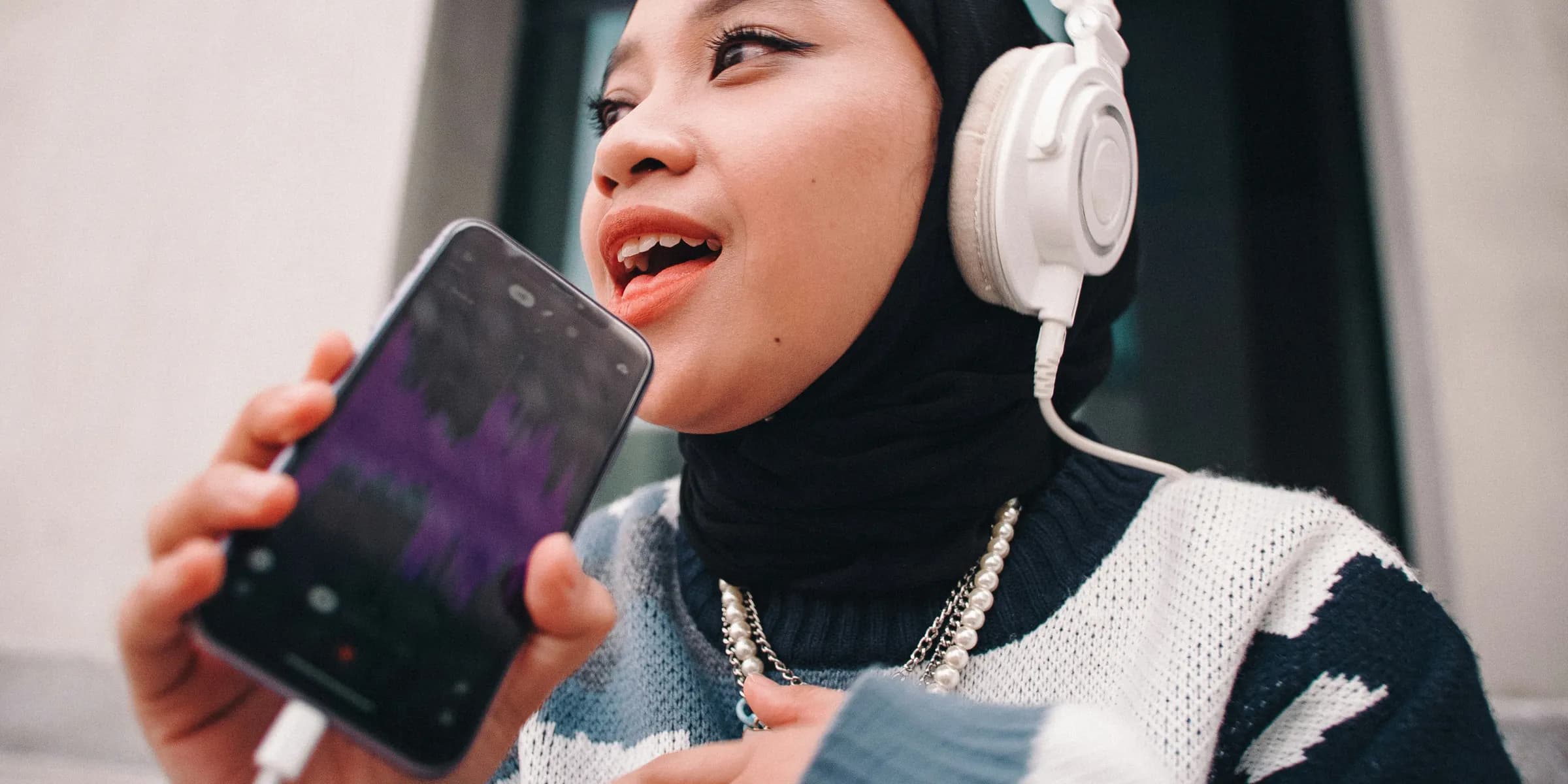 a woman wearing headphones and holding a phone