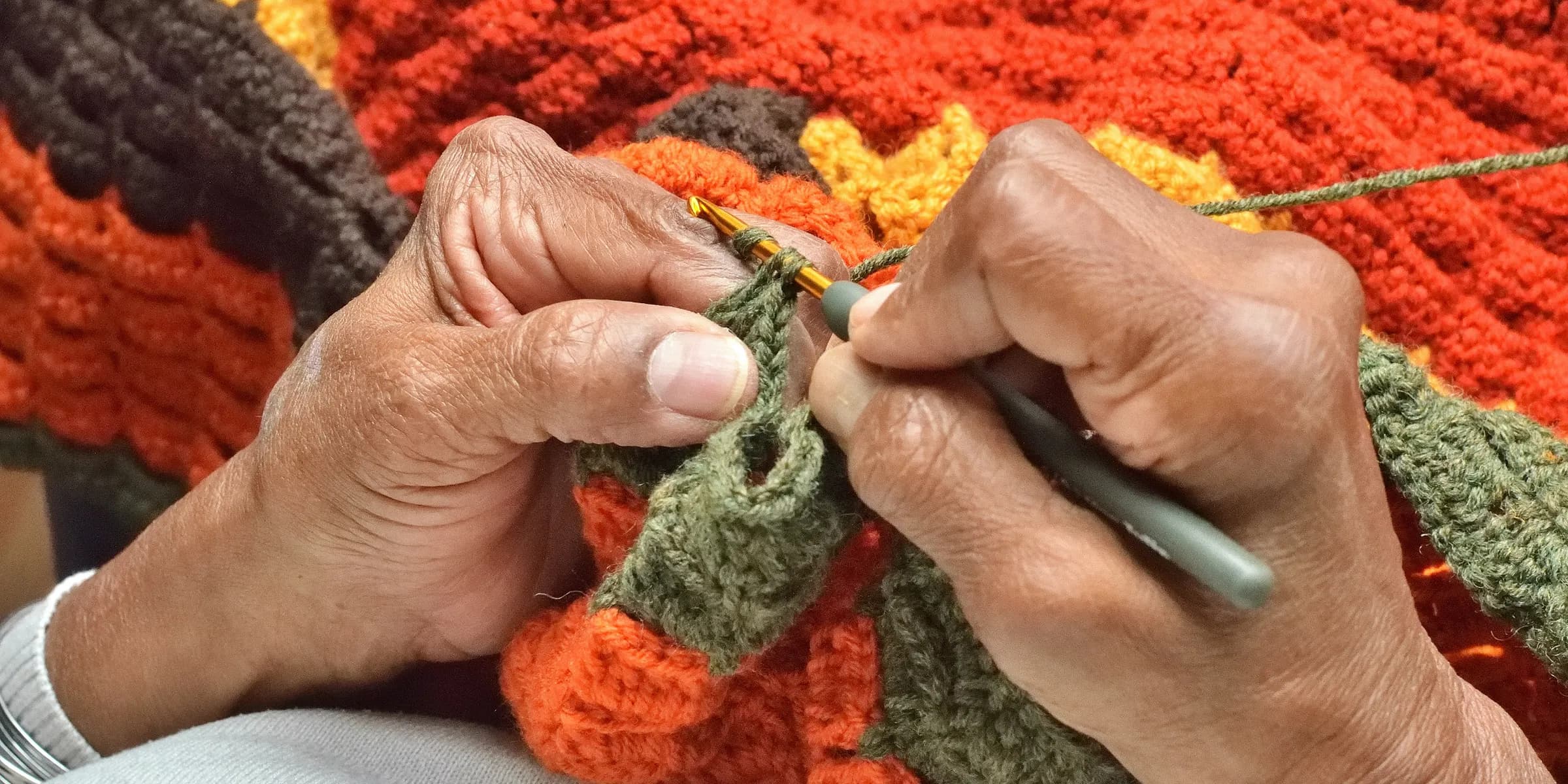 A person knitting a blanket with a pair of scissors