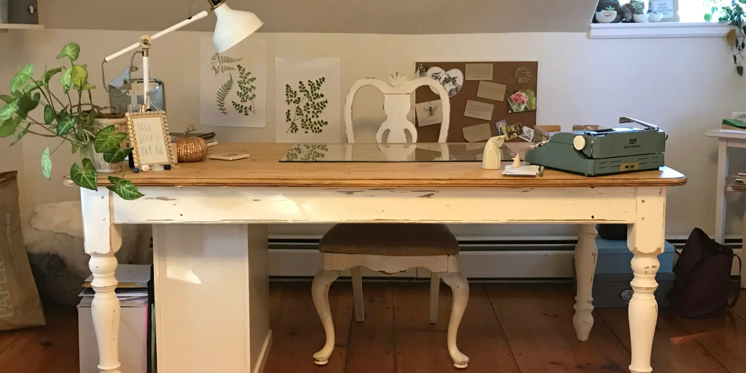 a room with a desk, chair, lamp and pictures on the wall