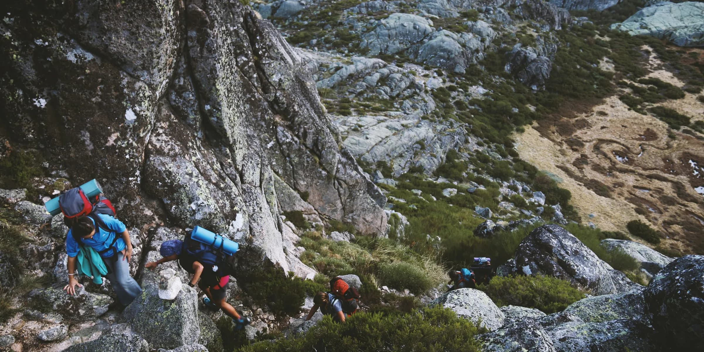 several mountain climbers on cliff of rock mountain at daytime