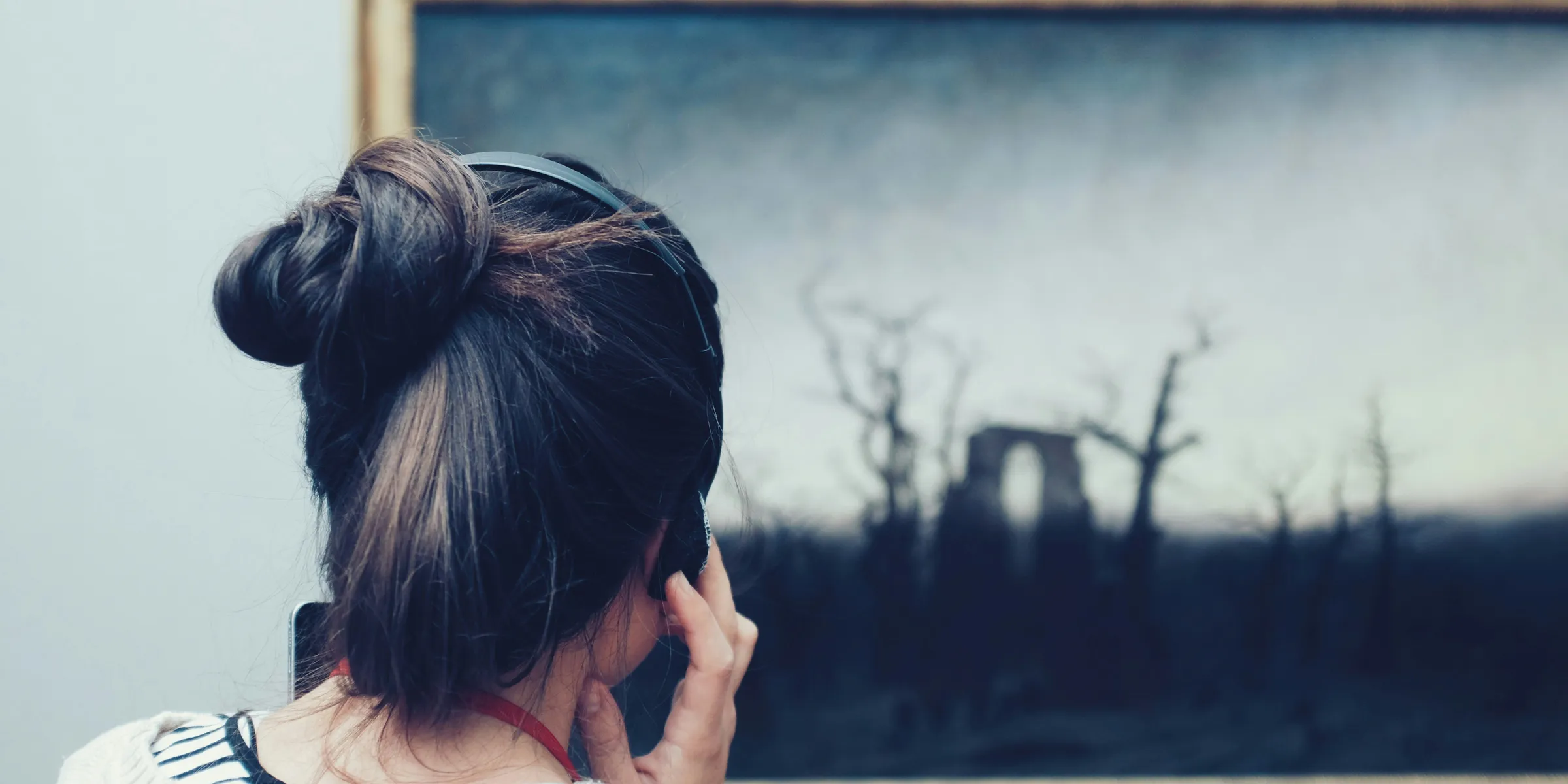 woman looking at a painting using headphones