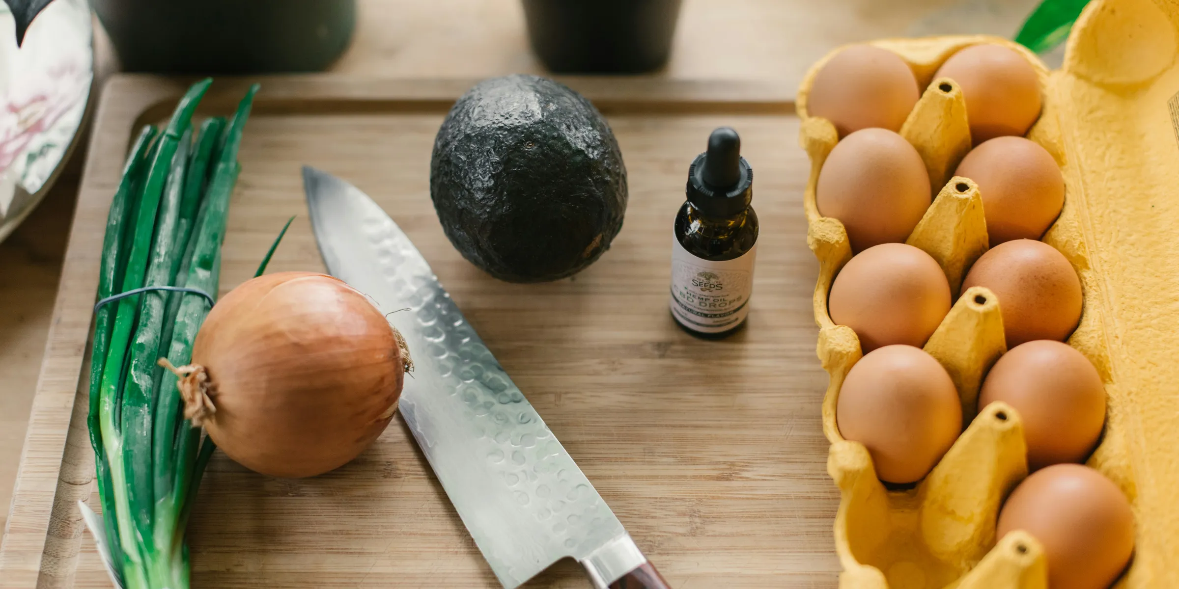 tray of eggs beside drop bottle, vegetables, and knife