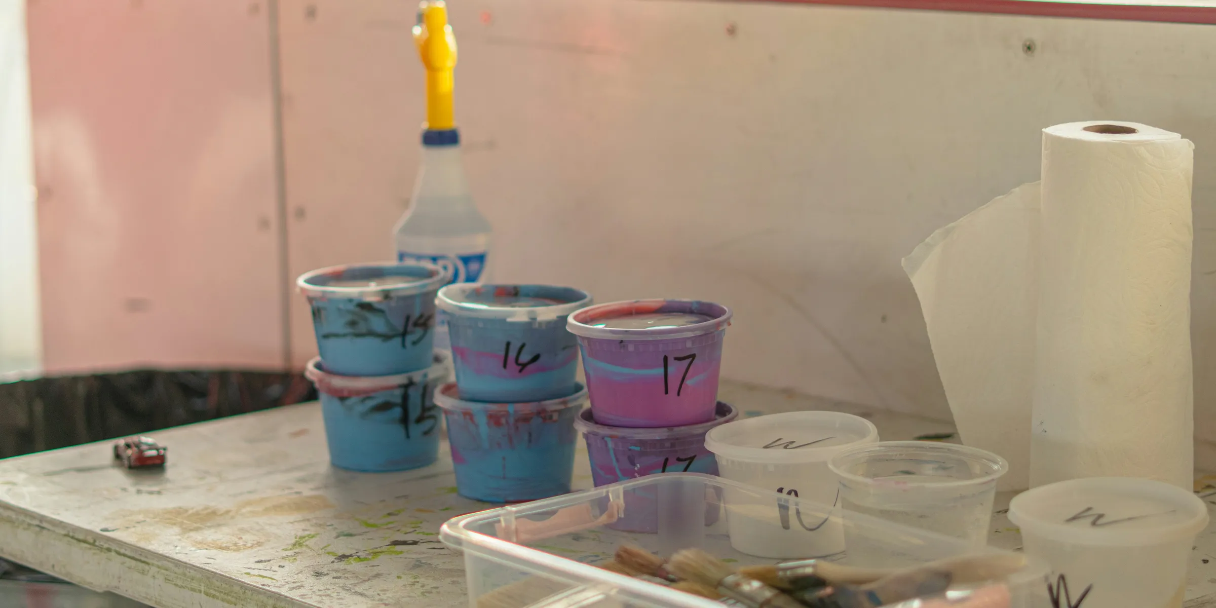 Paints, brushes, and supplies are on a work table.
