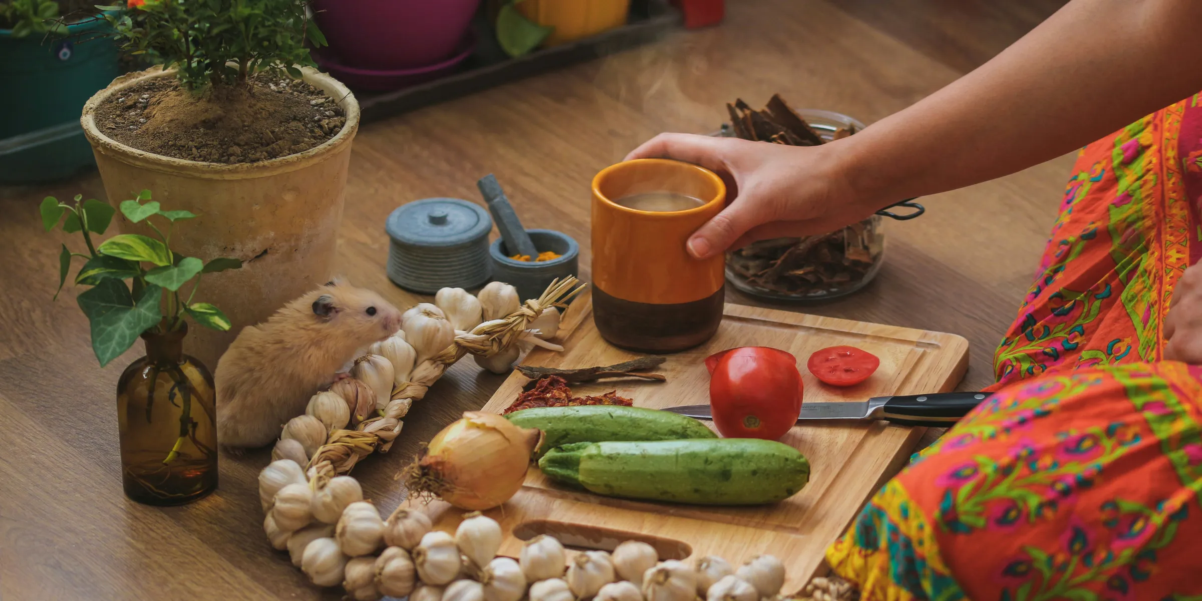 person having coffee while slicing vegetables