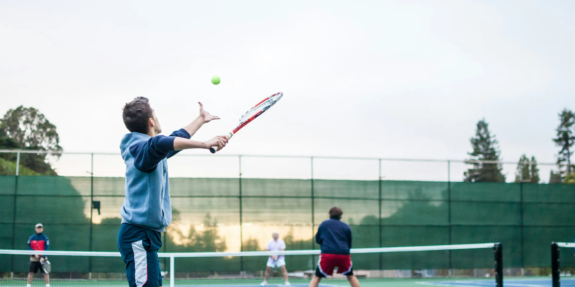 four men playing double tennis during daytime