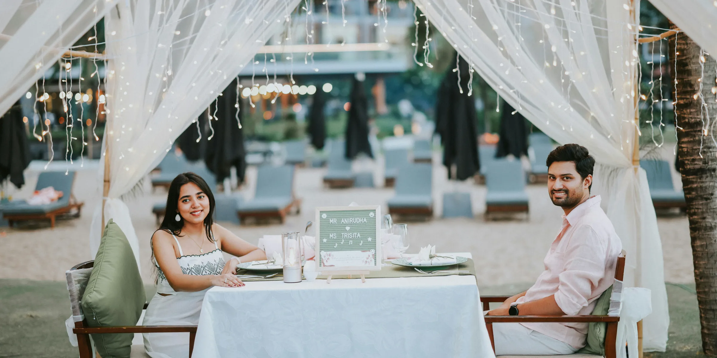 Couple having romantic dinner on beach under canopy lights