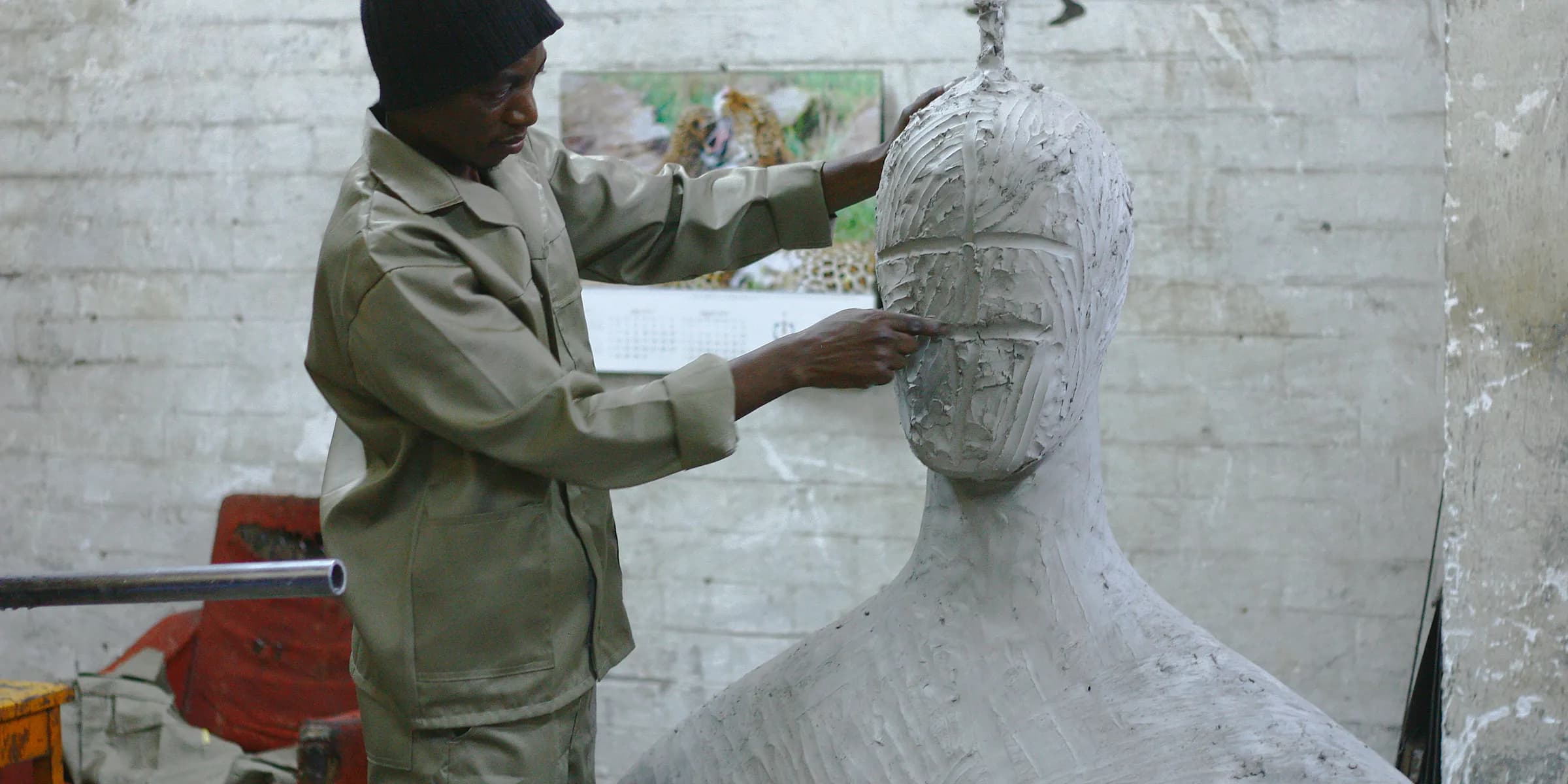 A sculptor works in his studio sculpting a large white body and head