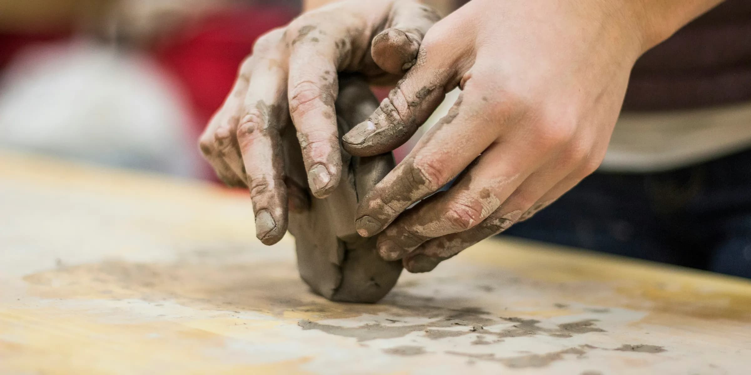 A clay stained hand of a potter engaging in a craft work of pottery or molding