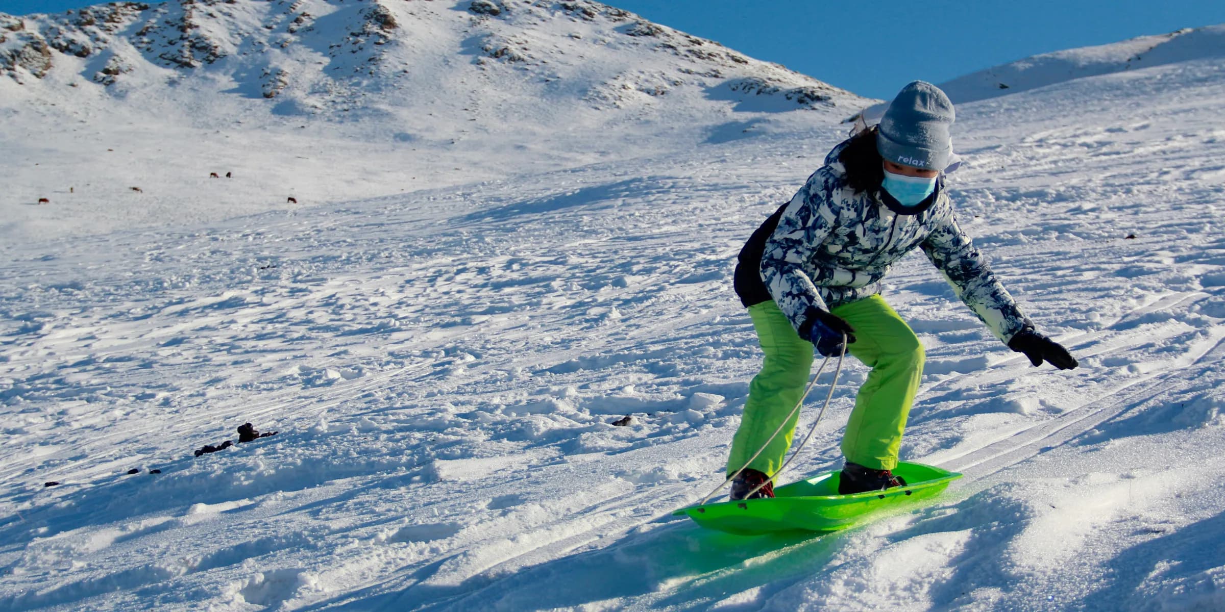 man in black jacket and green pants riding green snowboard on snow covered mountain during daytime