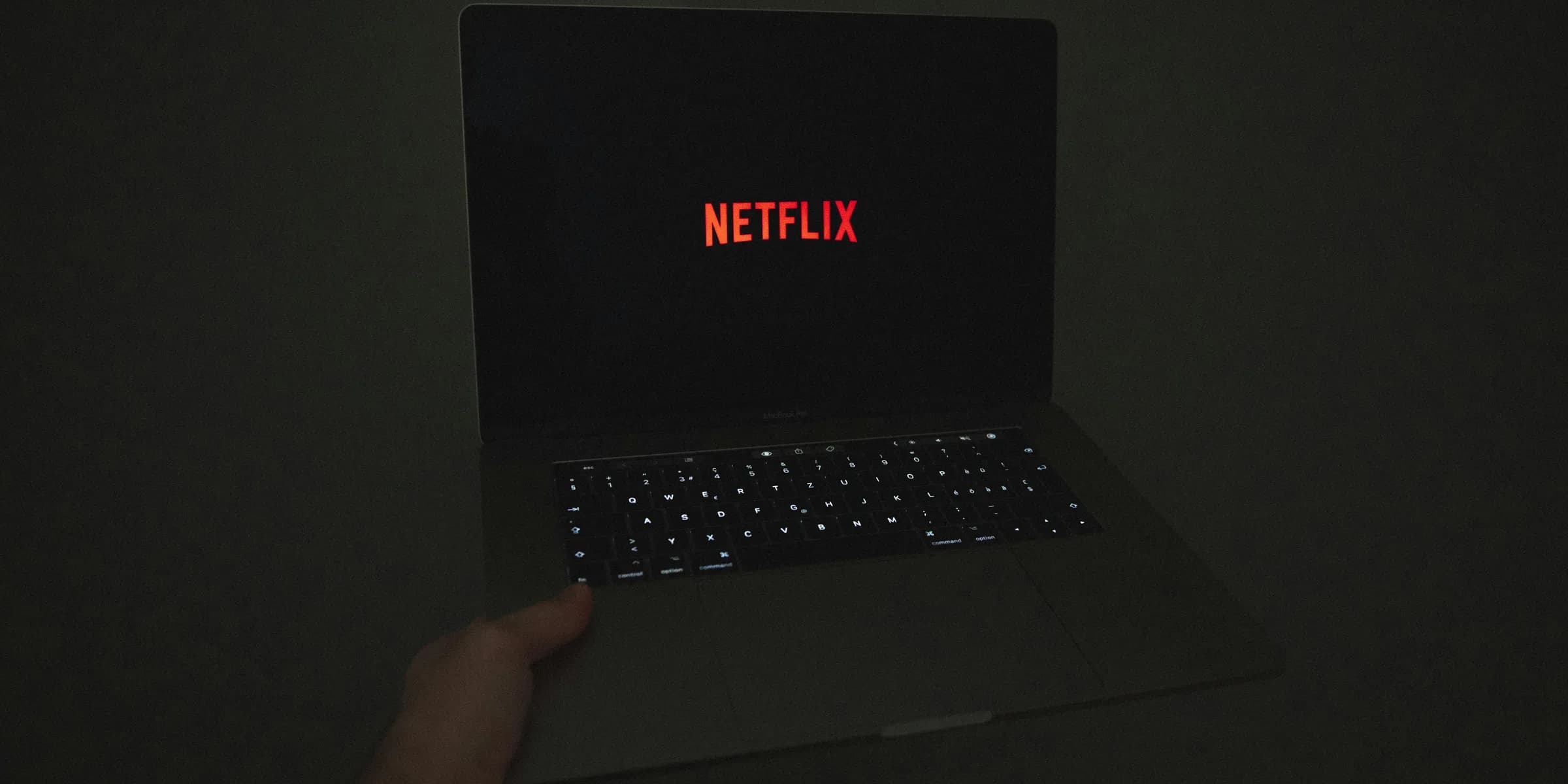 a person holding a laptop with the word netflix on the screen