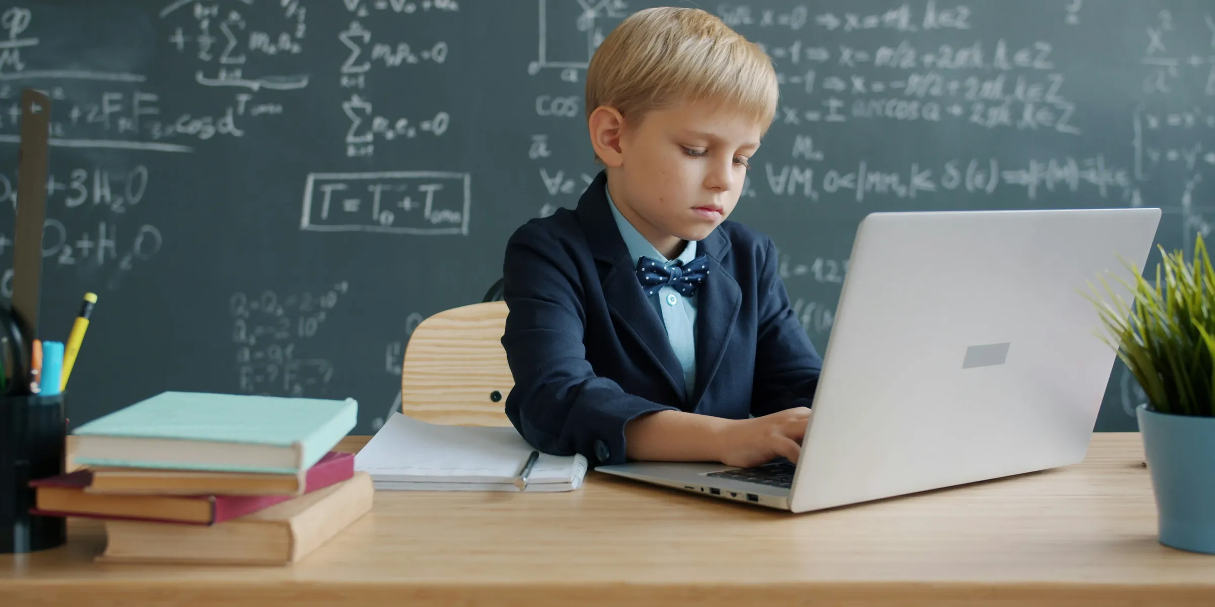 Boy in suit using laptop in classroom