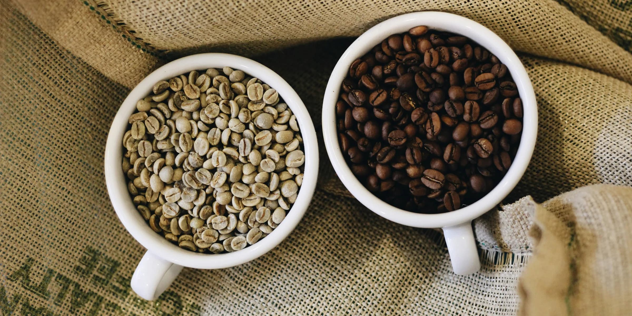 two white cups filled with coffee beans sitting on top of a couch
