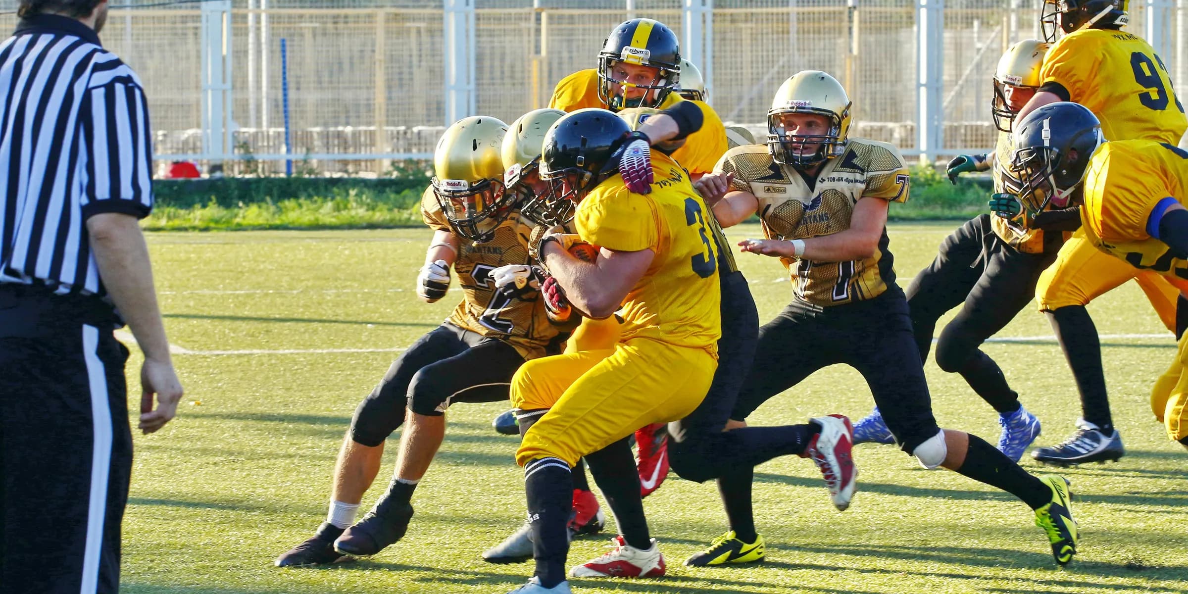 people playing american football with referee on the field during daytime