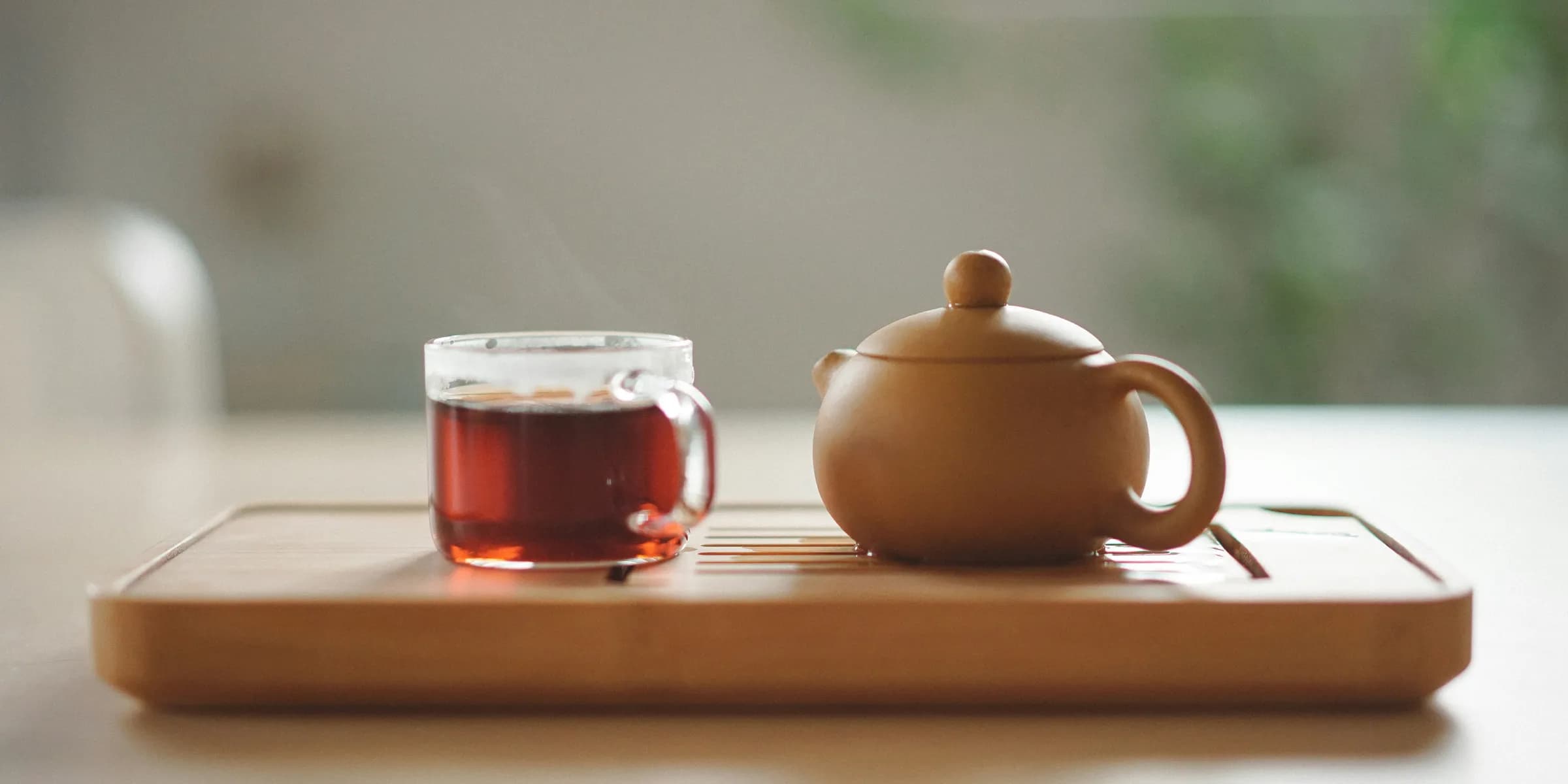 clear glass cup with tea near brown ceramic teapot