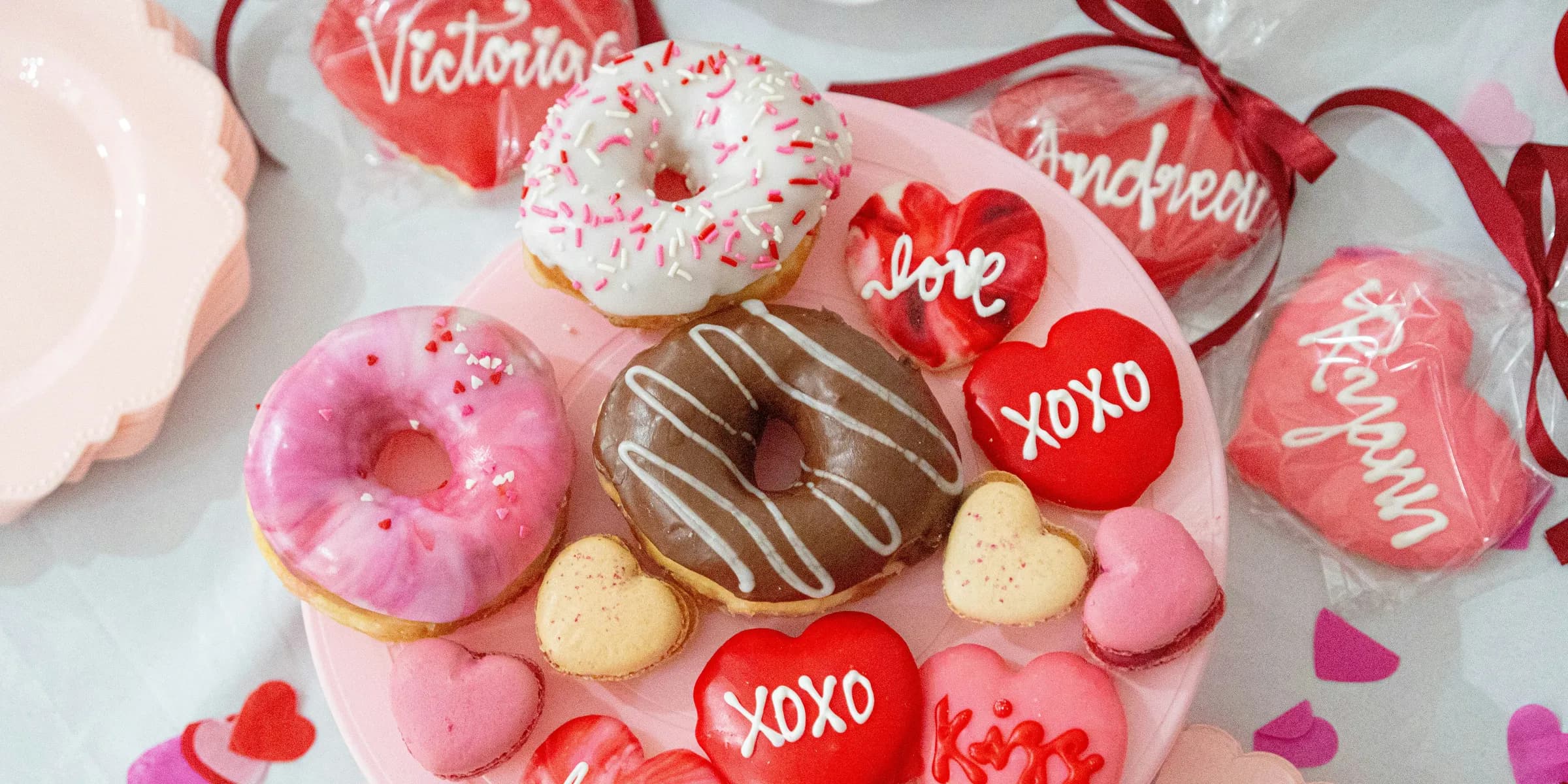A valentine's day table with a heart shaped plate of donuts