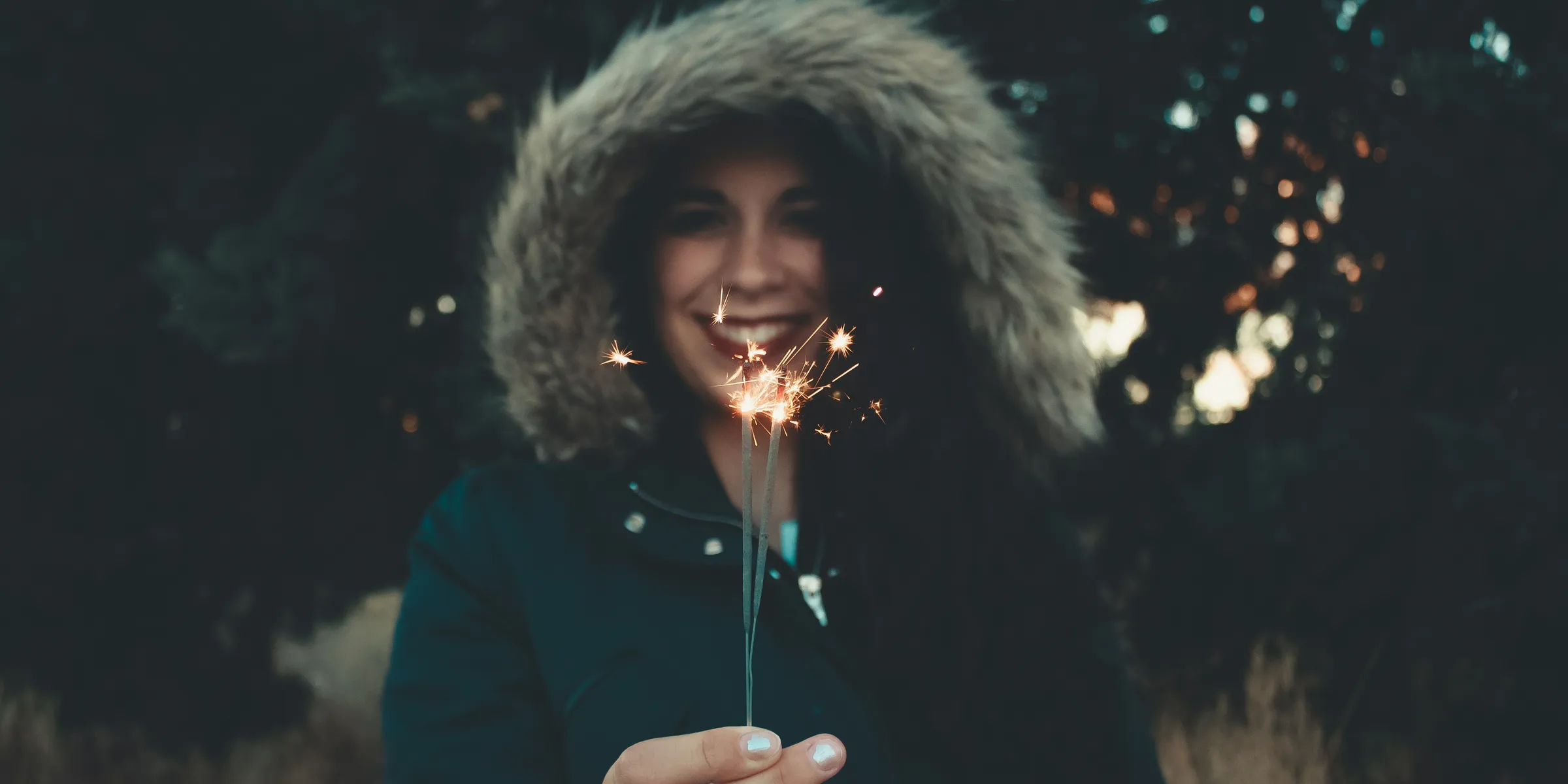 woman in fur-trim coat holding sparkler