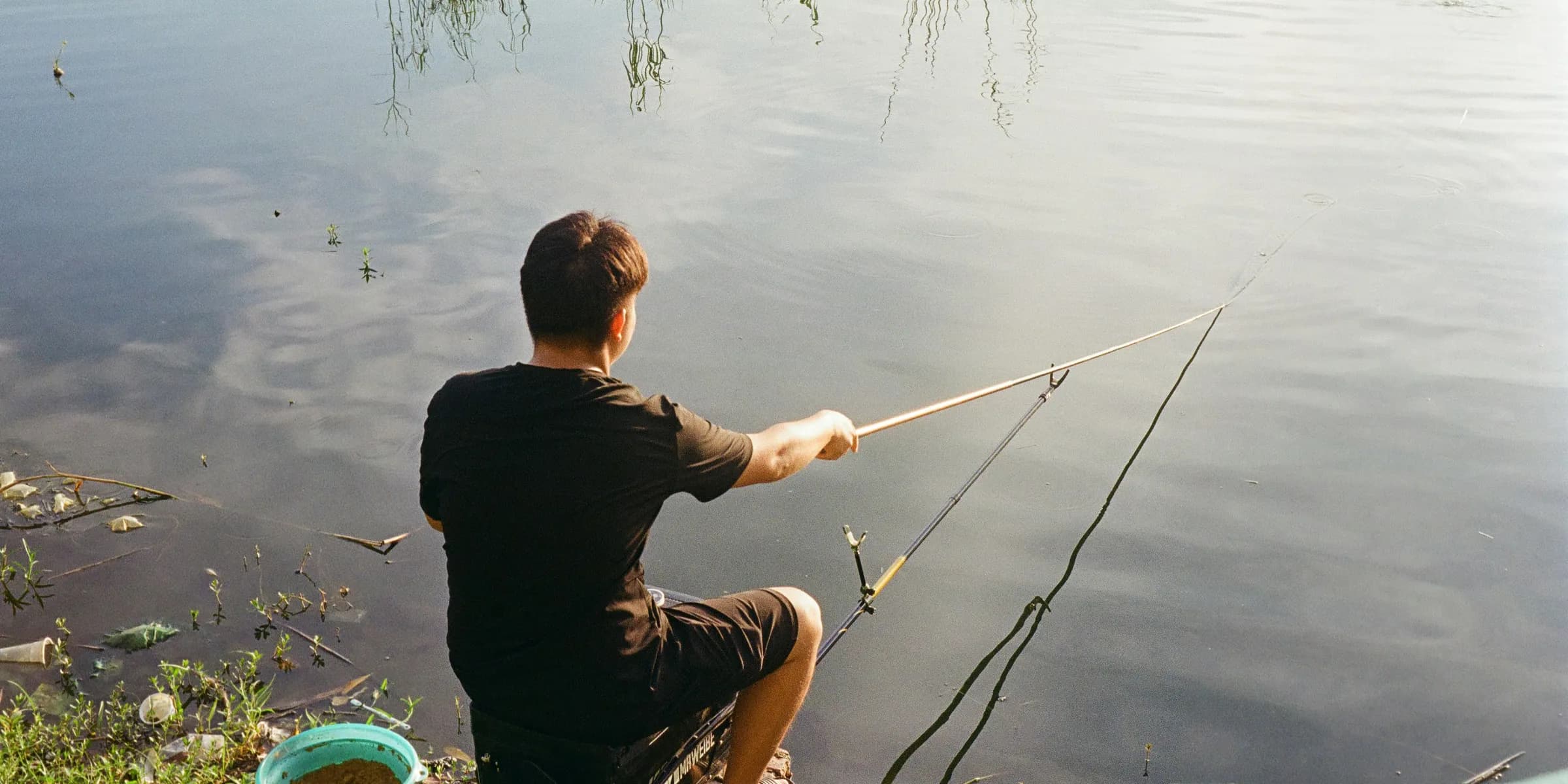 Man fishing by the water with a rod.
