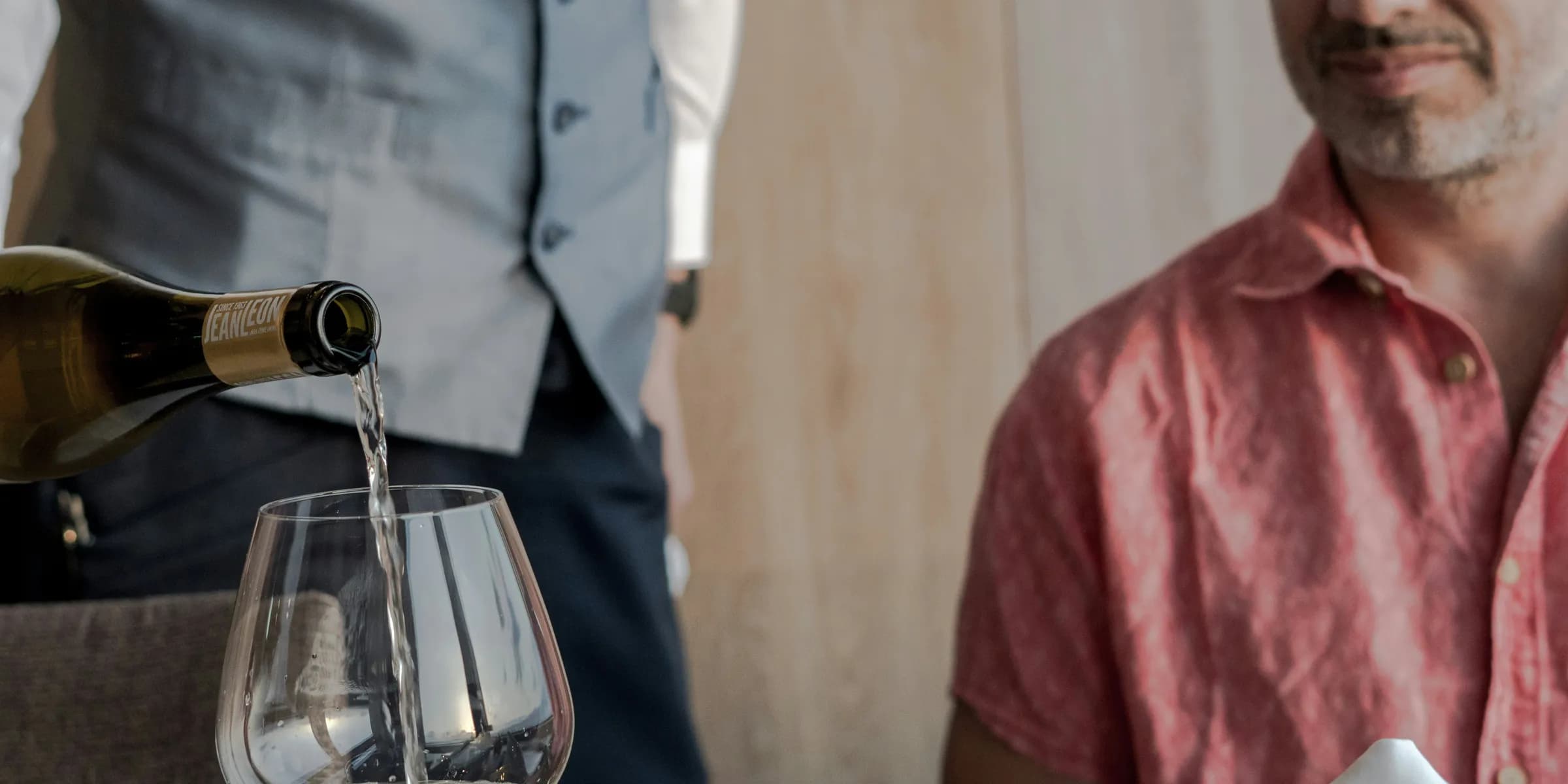 A man pouring a glass of wine at a table