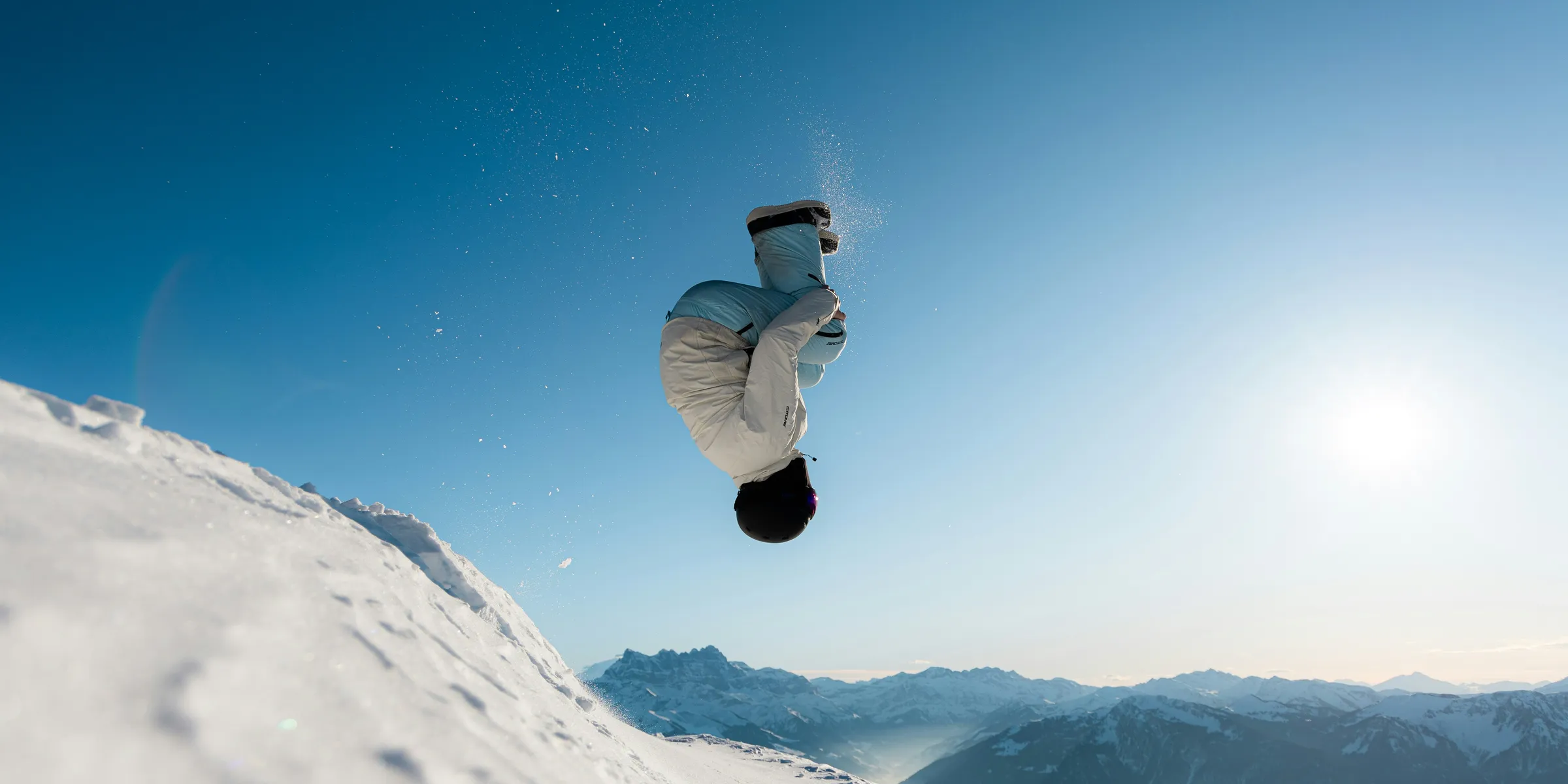Snowboarder flips in mid-air against clear blue sky