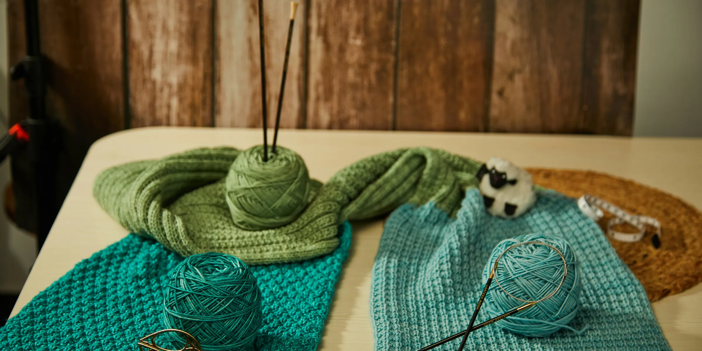 a table topped with yarn and knitting needles