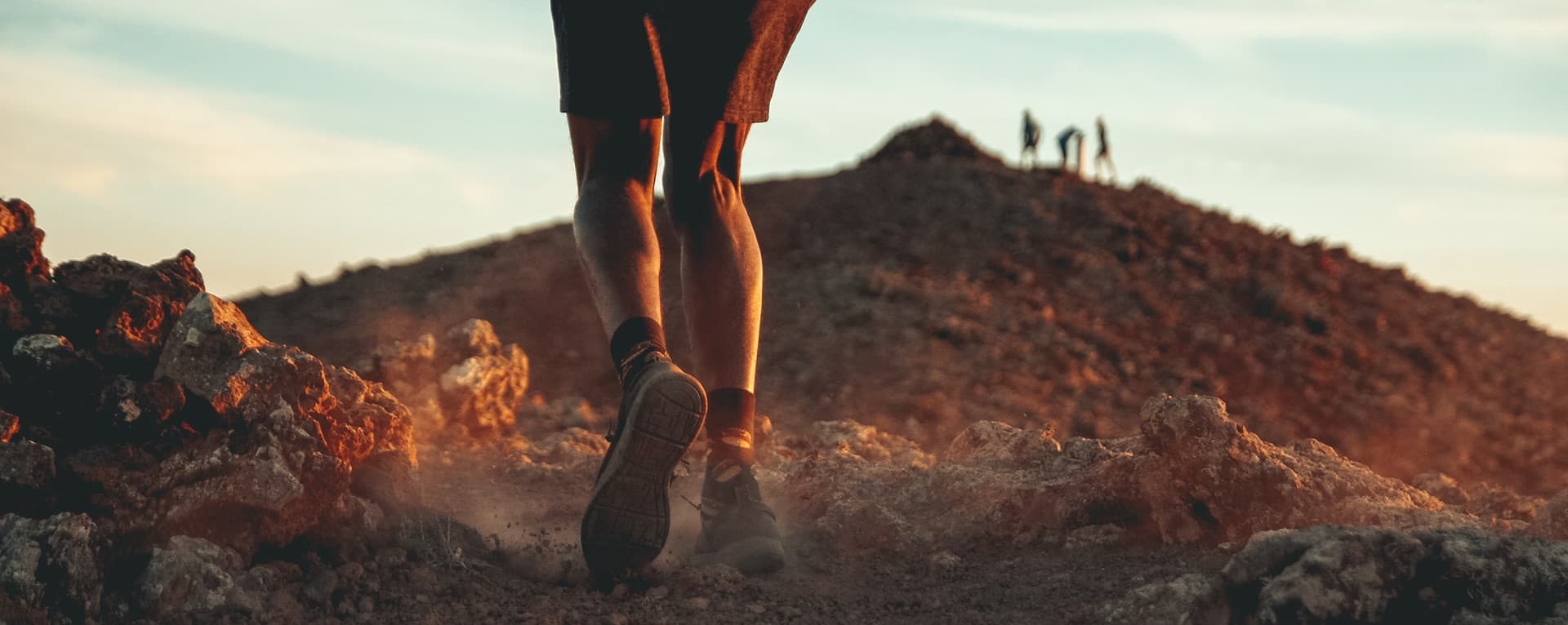 Close-up photo of a runner's legs on a rocky trail at sunset, capturing the raw power and purpose of modern running. This image evokes themes of sustainability, strength, and the future of outdoor performance.